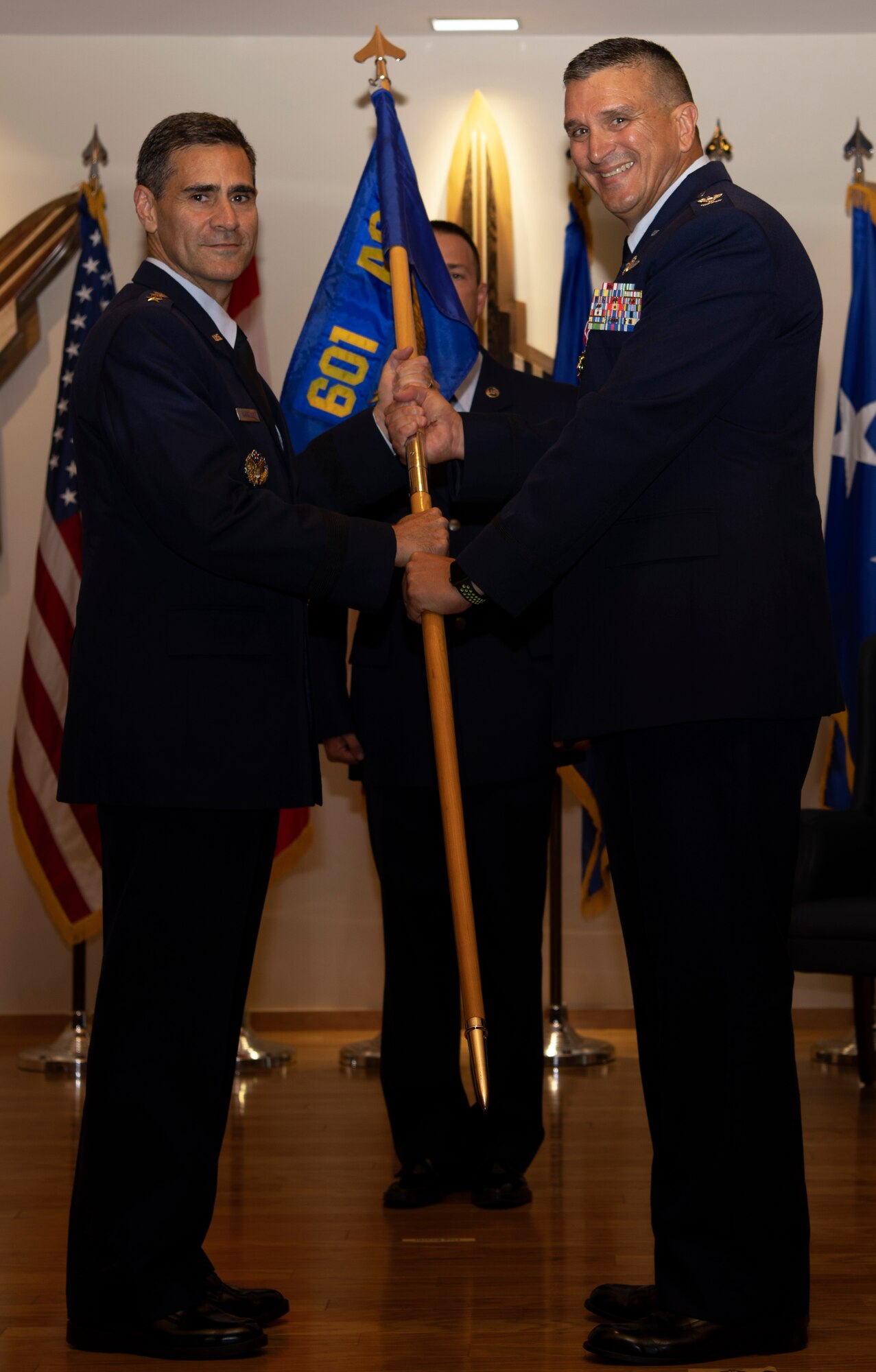 Col. Michael Valle, former 601st Air Operations Center commander, passes the ceremonial flag to Lt. Gen. Marc Sasseville, Continental U.S. North American Aerospace Defense Command Region - First Air Force (Air Forces Northern) commander, during the 601st Air Operations Center change of command ceremony at Tyndall Air Force Base, Florida on Sept. 26, 2019. The passing of the flag symbolizes Valle's passing of command to Col. Greg Krane, the new commander of the 601st AOC. (U.S. Air Force photo by Senior Airman Cheyenne Larkin)
