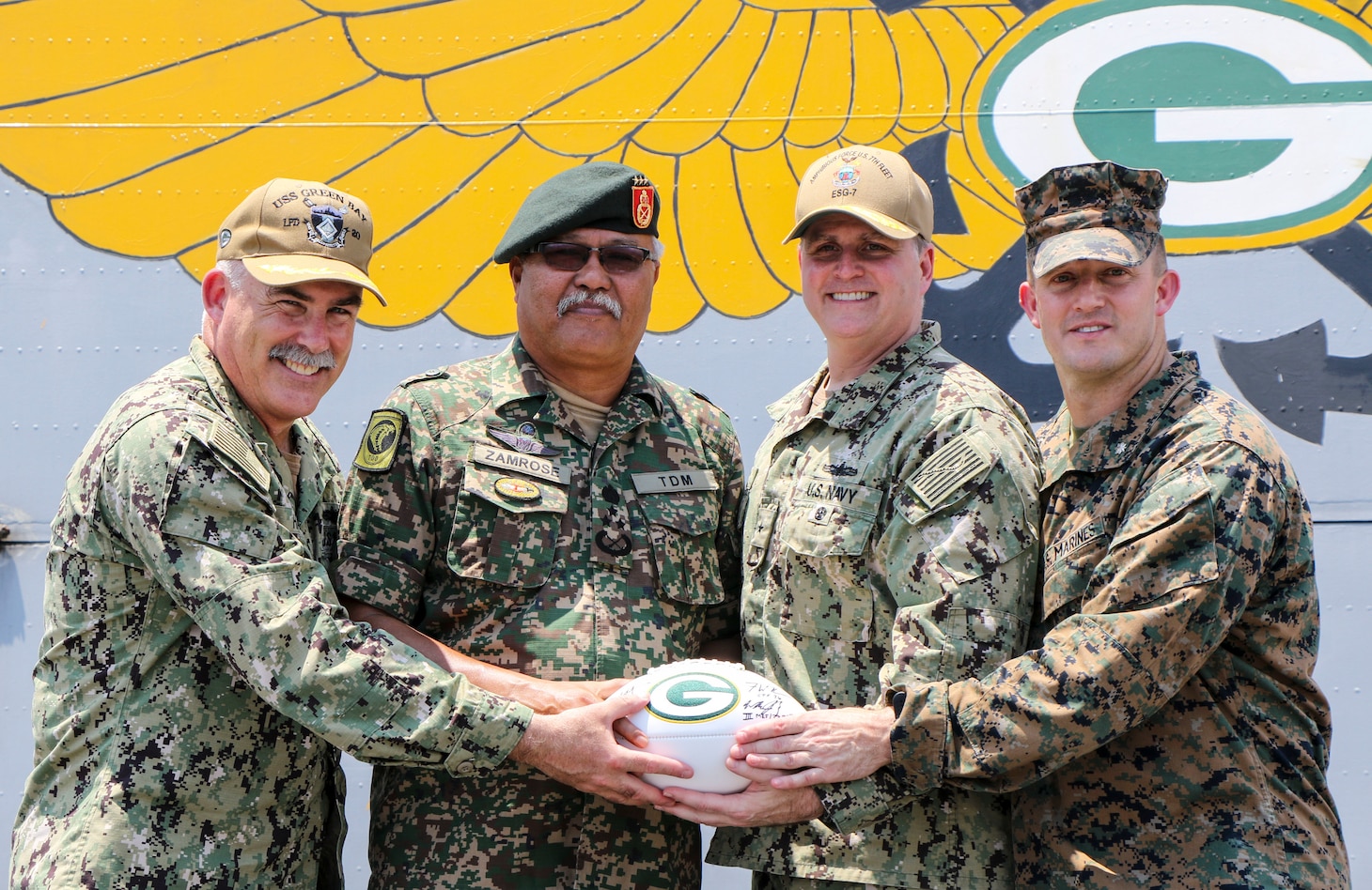 CELEBES SEA (Sept. 30, 2019) Captain Michael Harris, commanding officer of the amphibious transport dock ship USS Green Bay (LPD 20), Malaysian Armed Forces (MAF) Lt. Gen. Dato’ Wira Zambrose bin Mohd Zain, Army Field Eastern Commander, Rear Adm. Fred Kacher, commander of Expeditionary Strike Group 7, and Lt. Col. William Jacobs, commander of troops, 3rd Marine Division, pose for a photo with a Green Bay Packers football given as a memento during an opening ceremony for exercise Tiger Strike 2019. Tiger Strike focuses on strengthening combined U.S. and Malaysian military interoperability and increasing combat readiness through amphibious operations and cultural exchanges between the MAF and the U.S. Navy, Marine Corps team.