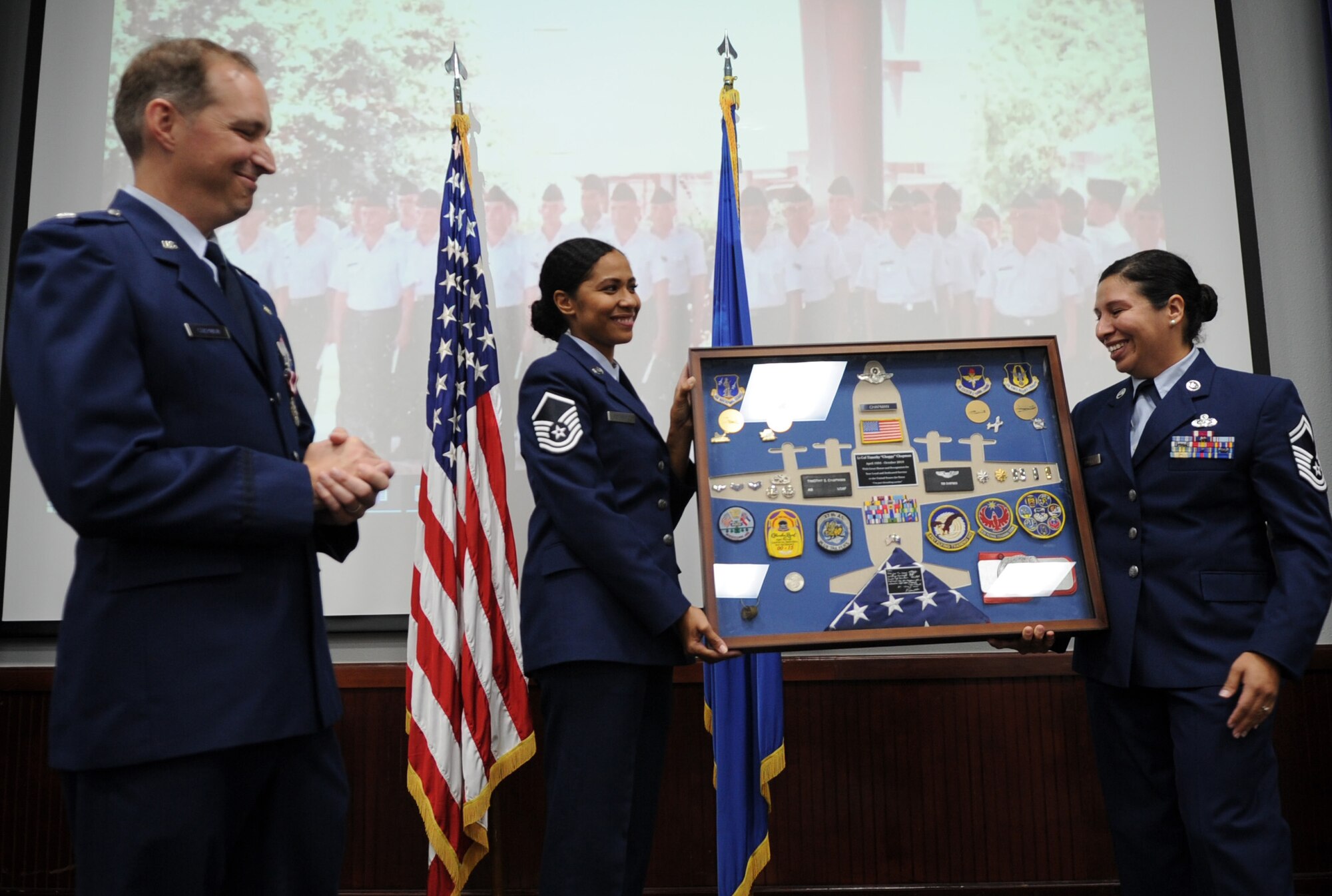 Former and current 340th Flying Training Group Undergraduate Flying Training Program noncommissioned officers in charge Master Sgt. Tainell Pettengill (left) Senior Master Sgt. Vianca Contreras present a special shadow box with items representing his career to Lt. Col. Timothy Chapman, former UFT program manager, during Chapman's Aug. 29 retirement ceremony at Joint Base San Antonio-Randolph, Texas. (U.S. Air Force photo by Debbie Gildea)