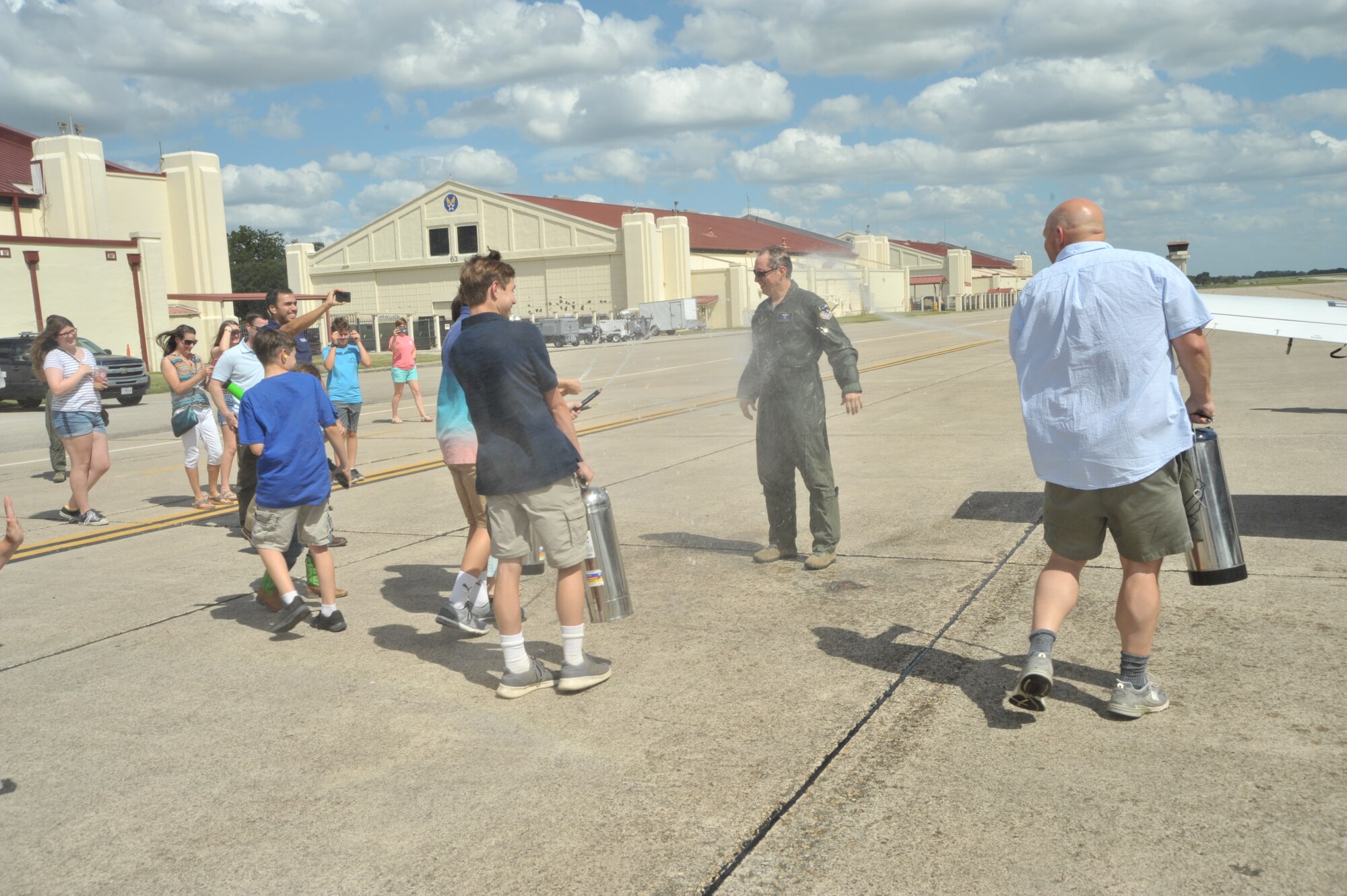 Lt. Col. Timothy Chapman, former 340th Flying Training Group Reserve Undergraduate Flying Training Program manager, takes a dousing from his brother and three of his sons following the colonel's June 18 final flight in the T-6 Texan at Joint Base San Antonio-Randolph, Texas. The fini flight and spray-down are traditional for retiring aircrew members. (U.S. Air Force photo by Debbie Gildea)