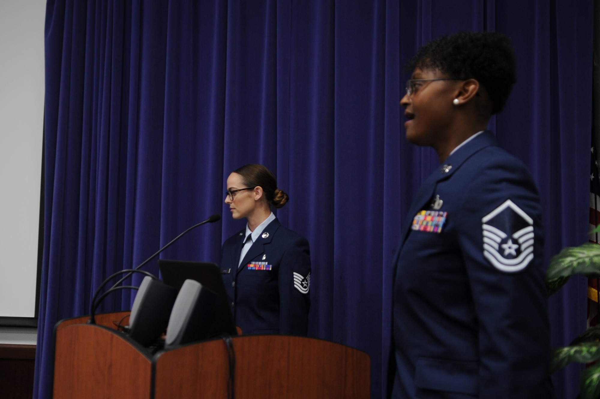 Master Sgt. Faith Wells, 340th Flying Training Group financial services section chief, sings the national anthem during the Aug. 29 retirement ceremony held at Joint Base San Antonio-Randolph, Texas for Lt. Col. Timothy Chapman, former 340th Flying Training Group Reserve Undergraduate Flying Training Program manager, while Tech. Sgt. Alecia Lovci, UFT staff and ceremony master of ceremonies, stands at attention. (U.S. Air Force photo by Debbie Gildea)