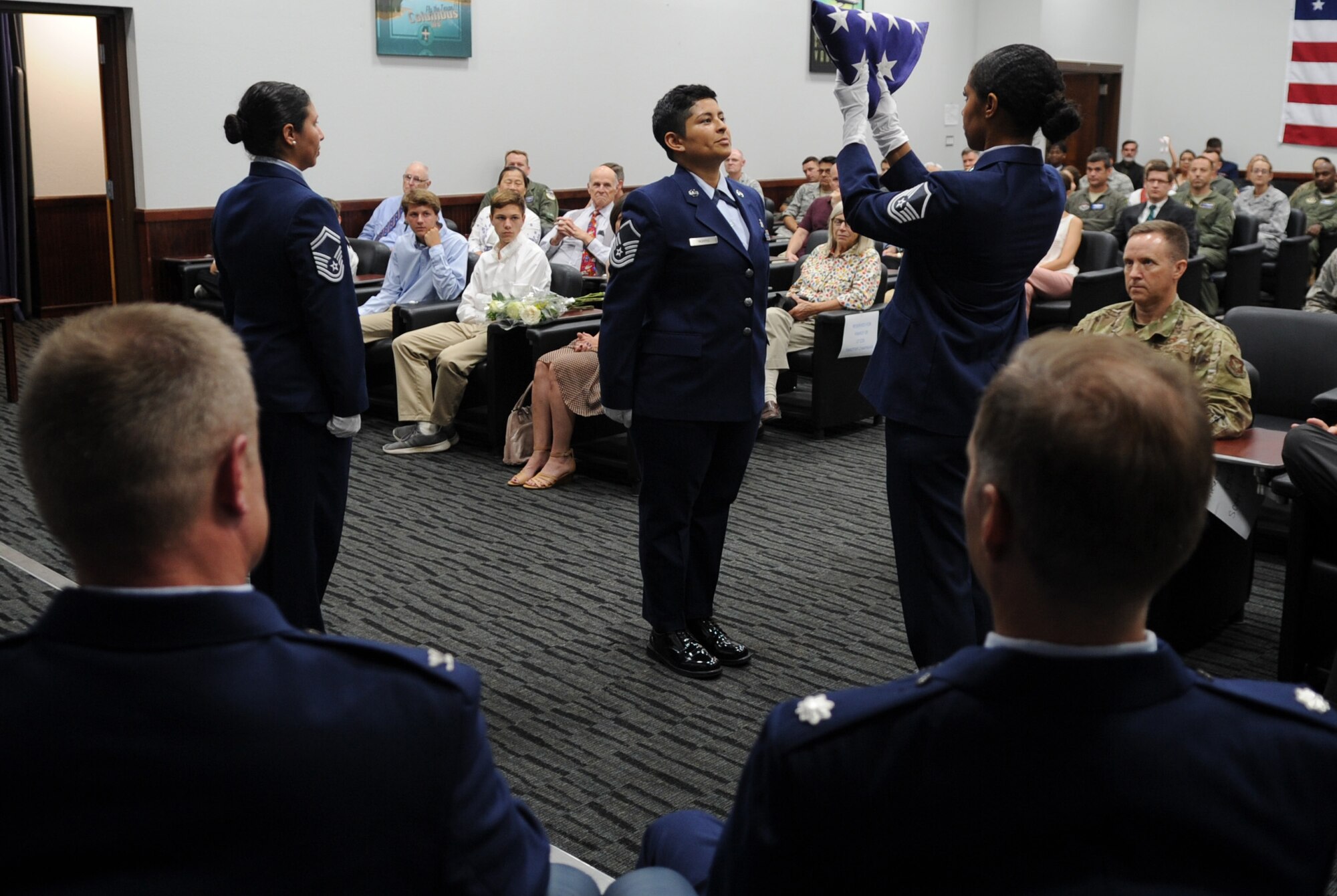 Master Sgt. Tainell Pettengill (right), 340th Flying Training Group Undergraduate Flying Training Program noncommissioned officer in charge, presents the U.S. flag to former UFT staff member Master Sgt. Digma Norris while detail chief former UFT NCOIC Senior Master Sgt. Vianca Contreras stands by during the flag folding ceremony performed in honor of retiring UFT program manager Lt. Col. Timothy Chapman during Chapman's Aug. 29 retirement ceremony at Joint Base San Antonio-Randolph, Texas. Contreras and Norris, now assigned to different units, made the trip to JBSA-Randolph to honor their former boss. (U.S. Air Force photo by Debbie Gildea)