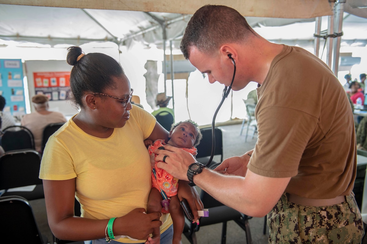 A Navy doctor examines a baby.