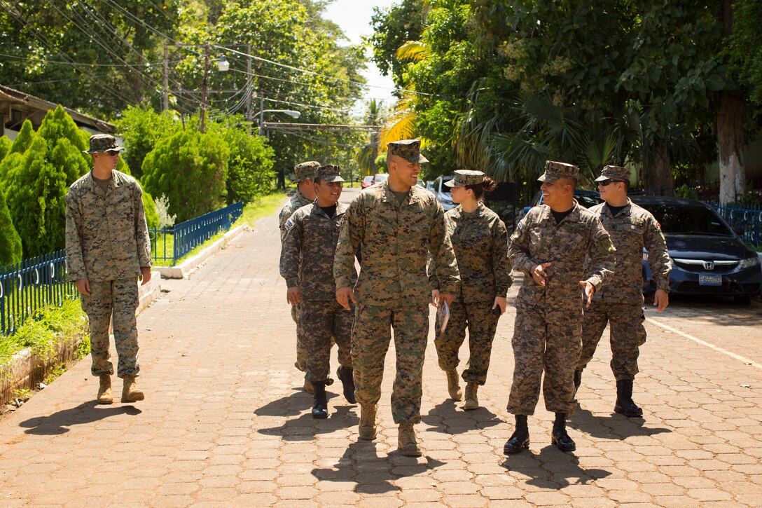 A group of military personnel walk and talk.