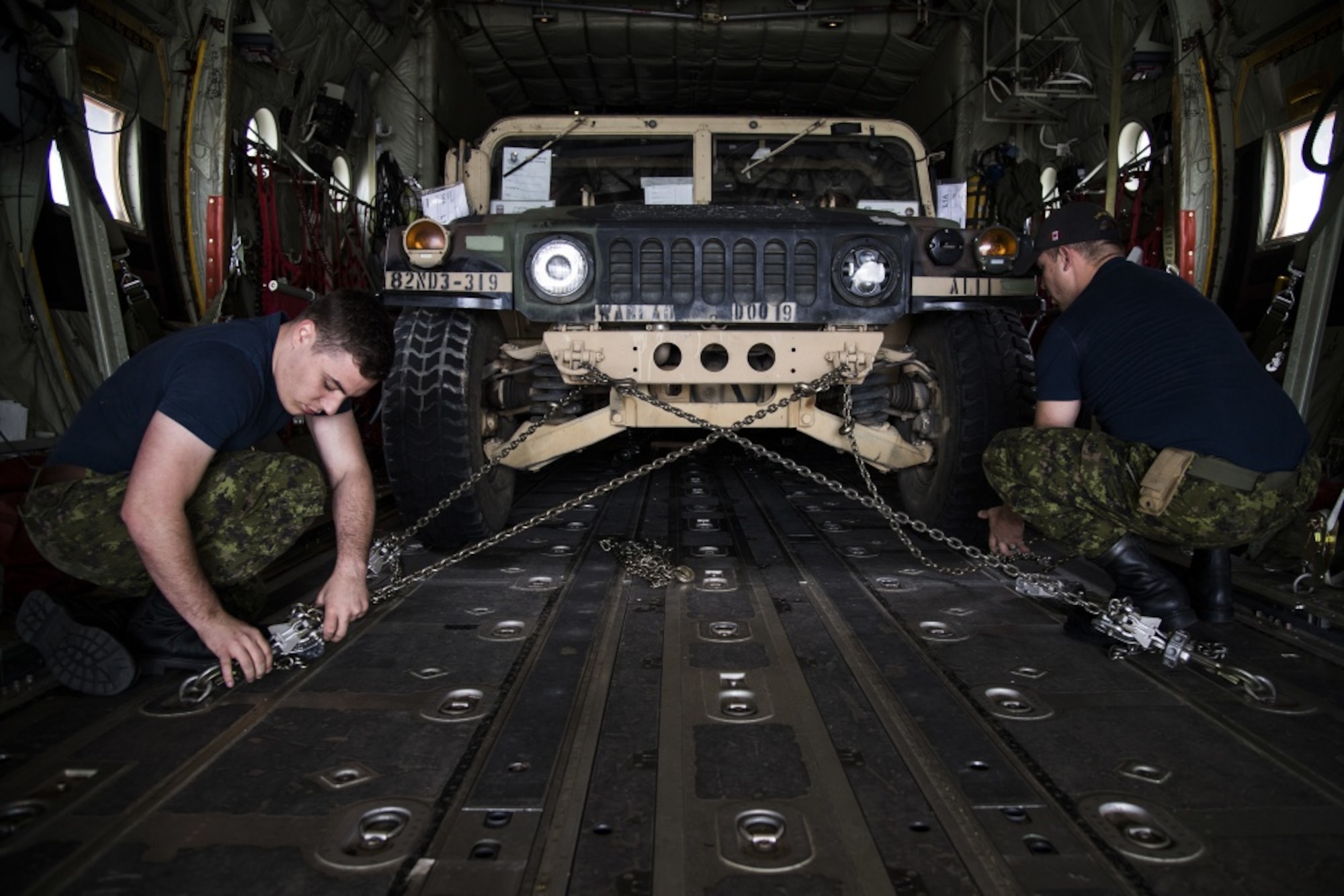 Royal Canadian Air Force CC-130J Super Hercules crew members, 436 Transport Squadron, assigned to 8 Wing Trenton, Trenton, Ontario, Canada, chain down a U.S. Army humvee onto the cargo bay in preparation for the Selah Creek air base opening training scenario during Mobility Guardian 2019, Fairchild Air Force Base, Washington, Sept. 14, 2019. Exercise Mobility Guardian is Air Mobility Command's premier, large scale mobility exercise. Through robust and relevant training, Mobility Guardian improves the readiness and capabilities of Mobility Airmen to deliver rapid global mobility and builds a more lethal and ready Air Force. (U.S. Air Force photo by Tech. Sgt. Larry E. Reid Jr.)
