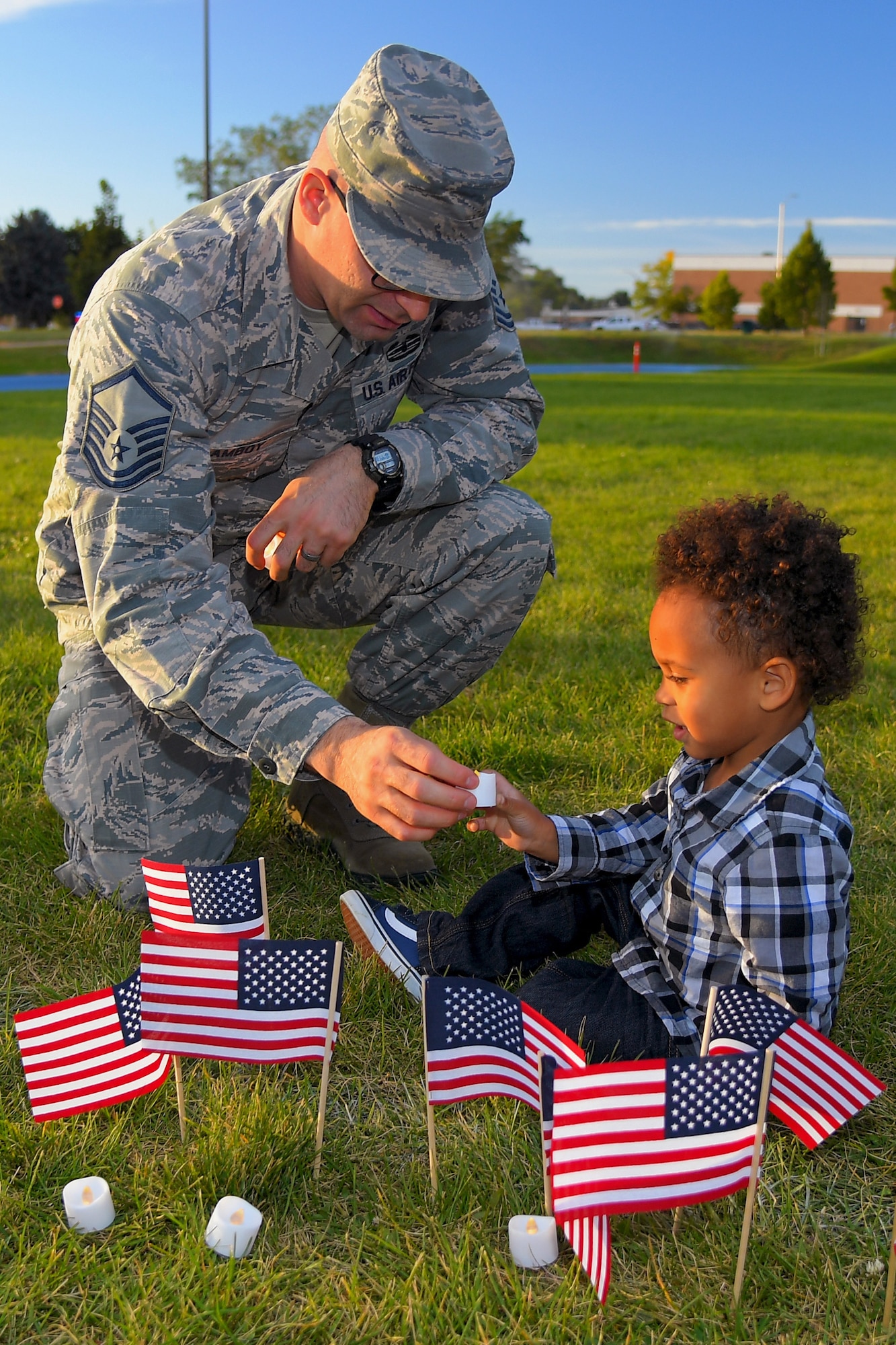 (Left to right) Master Sgt. Albert Lamboy, acting first sergeant for the 75th Logistics Readiness Squadron, helps his son Malachi place a candle during a Suicide Prevention Month candlelight vigil Sept. 26, 2019, at Hill Air Force Base, Utah. Throughout the day and during the vigil, Airmen placed flags in remembrance of a family member, friend or coworker who died by suicide. (U.S. Air Force Photo by Todd Cromar)