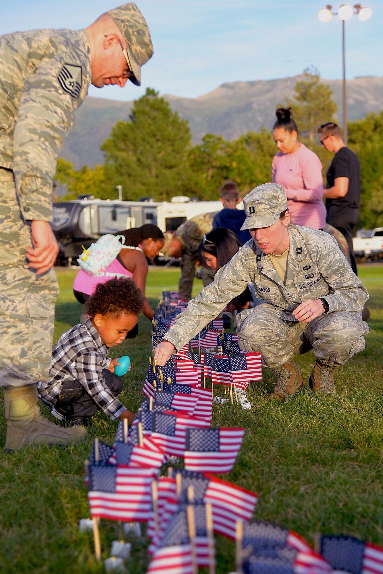 (Left to right) Master Sgt. Albert Lamboy, acting first sergeant for the 75th Logistics Readiness Squadron, his son Malachi, and Capt. Carly Lazos, 75th Air Base Wing, place candles during a Suicide Prevention Month candlelight vigil Sept. 26, 2019, at Hill Air Force Base, Utah. Throughout the day and during the vigil, Airmen placed flags in remembrance of a family member, friend or coworker who died by suicide. (U.S. Air Force Photo by Todd Cromar)