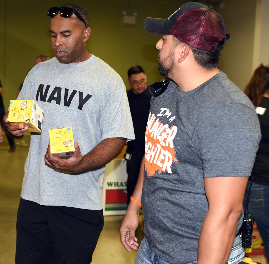 Petty Officer 1st Class Vincent Barnes (left), a leading petty officer assigned to Navy Recruiting Station North East, speaks with Mario Sanchez, a San Antonio Food Bank volunteer coordinator, regarding the expiration date on food items Sept. 27.