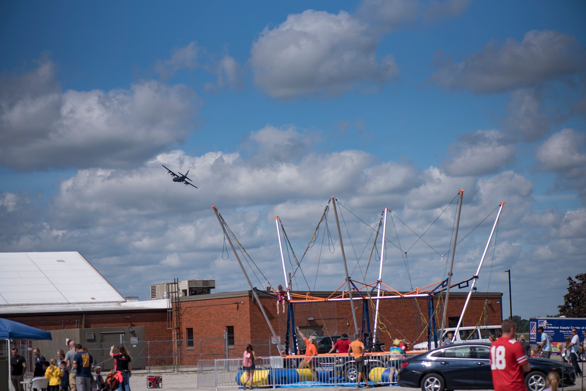 Photo of people jumping on a trampoline while a C-130's flies over