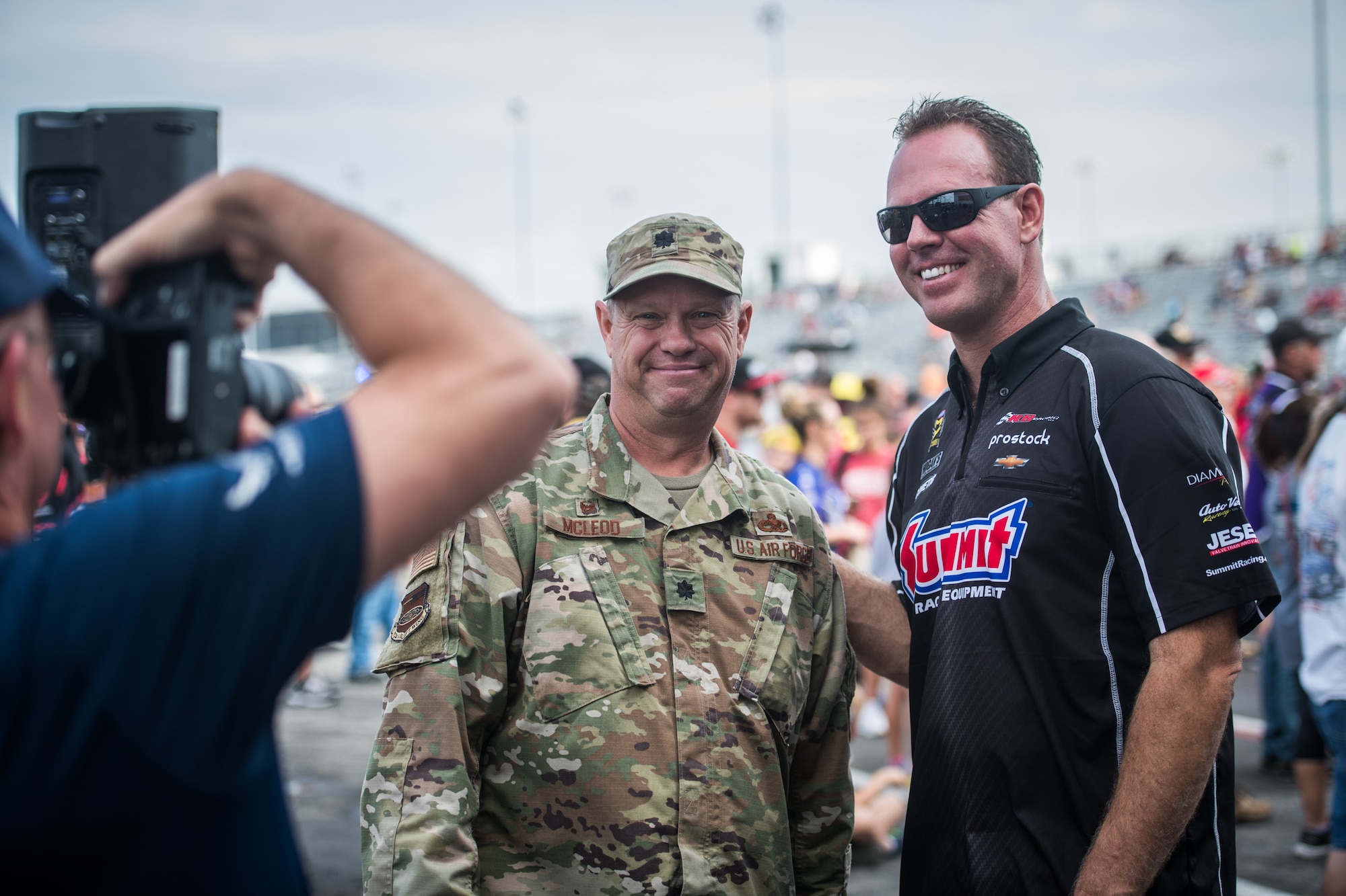 Lt. Col. William McLeod, 932nd Maintenance Group commander,  poses for a photo with a National Hot Rod Association race car driver just before the opening ceremony, Sept. 29, 2019, World Wide Technology Raceway at Gateway Motorsports Madison Illinois. McLeod was honored as a special guest for the day and presented a NHRA challenge coin. (U.S. Air Force photo by Master Sgt. Christopher Parr)