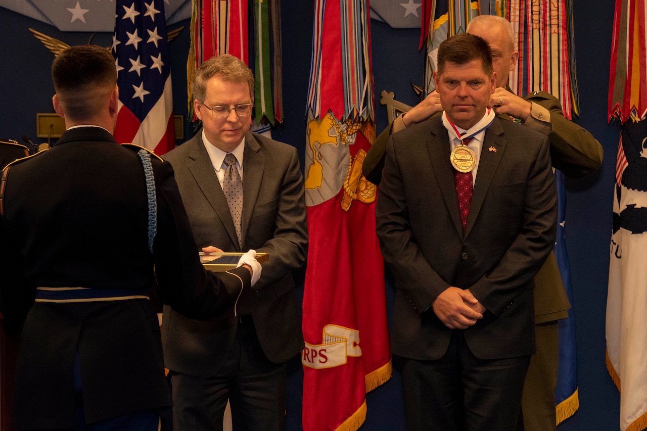Man presents award to another man.
