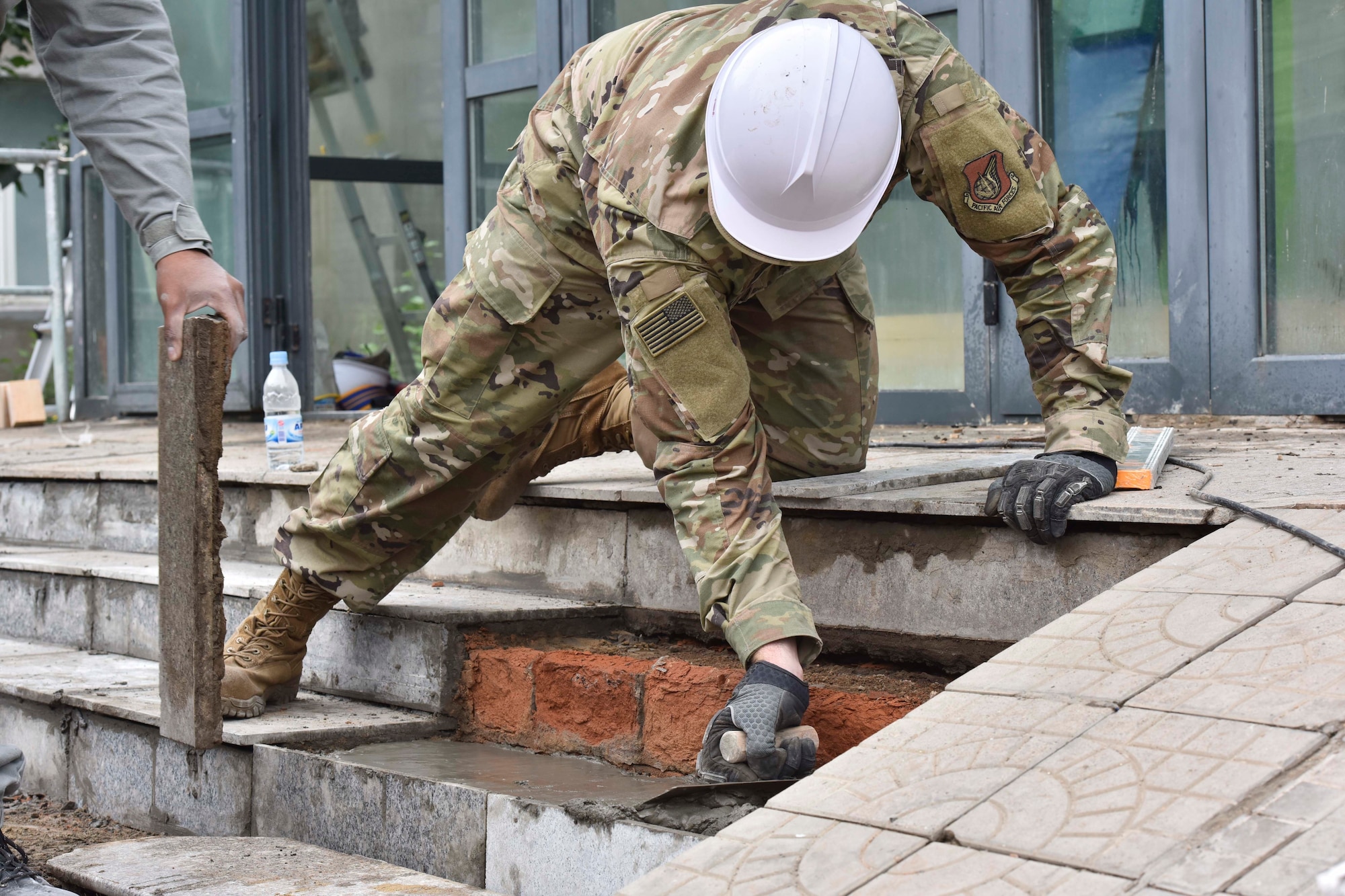 A U.S. Air Force civil engineer repairs steps in front of a school, July 30, 2019, during Pacific Angel 19-3 in Bayangol Soum, Mongolia. PAC ANGEL is a multilateral humanitarian assistance civil military engagement, improving military-to-military partnerships in the pacific through medical health outreach, civic engineering projects and subject matter expert exchanges between U.S. service members, multinational militaries, nongovernmental organizations, and Mongolian military and civilian participants. (U.S. Air Force photo by Senior Airman Eric M. Fisher)