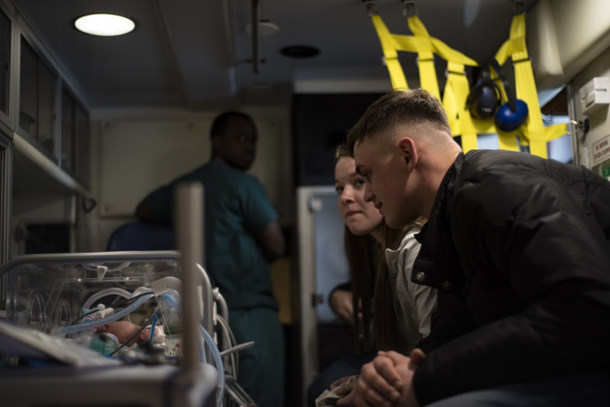 Parents, Specialist Cody McFall and Private First Class Cheyenne Evans, U.S. Army Camp Walker, Republic of Korea, 188th Military Police Company soldiers, look on as one of their newborn twins sleeps before an aeromedical evacuation mission, March 30, 2020, at Osan Air Base, Republic of Korea.