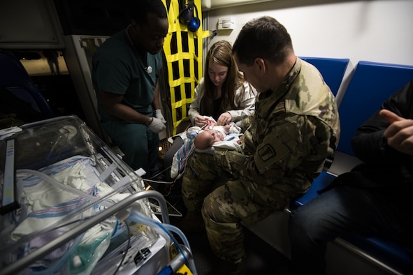 Medics from the 51st Medical Group watch as U.S. Army Private First Class Cheyenne Evans, 188th Military Police Company, Camp Walker, Republic of Korea, reunites with her newborn, baby McFall, prior to an aeromedical evacuation mission, March 30, 2020, at Osan Air Base, Republic of Korea.