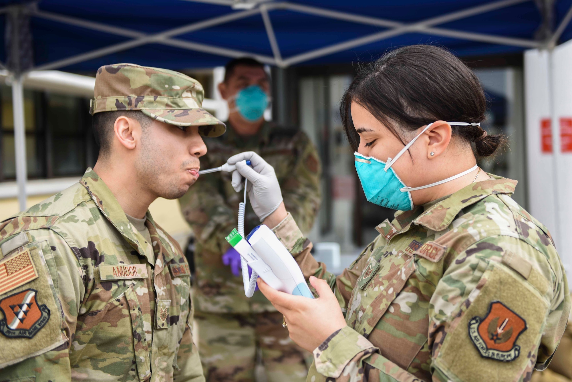 U.S. Air Force Staff Sgt. Melissa Lozada, 39th Medical Support Squadron resource management office non-commissioned officer in charge, right, checks a visitor’s temperature, March 20, 2020, at Incirlik Air Base, Turkey. In response to the COVID-19 pandemic, the 39th Medical Group has altered its operations to focus on acute care cases. (U.S. Air Force photo by Staff Sgt. Joshua Magbanua)