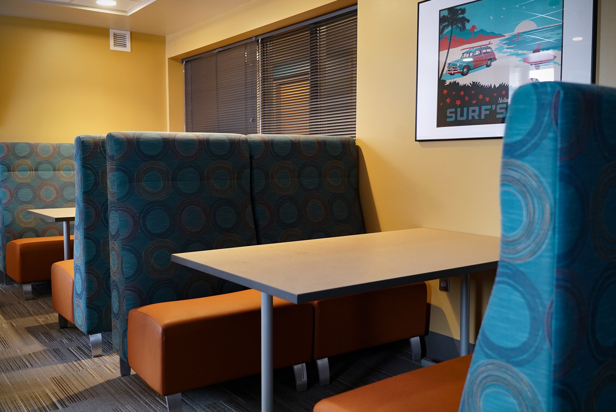 Café-style booths decorate one of the lounges in Gray Hall Dorm. The booth seat backs are blue, connected to a complementary orange seat bench.