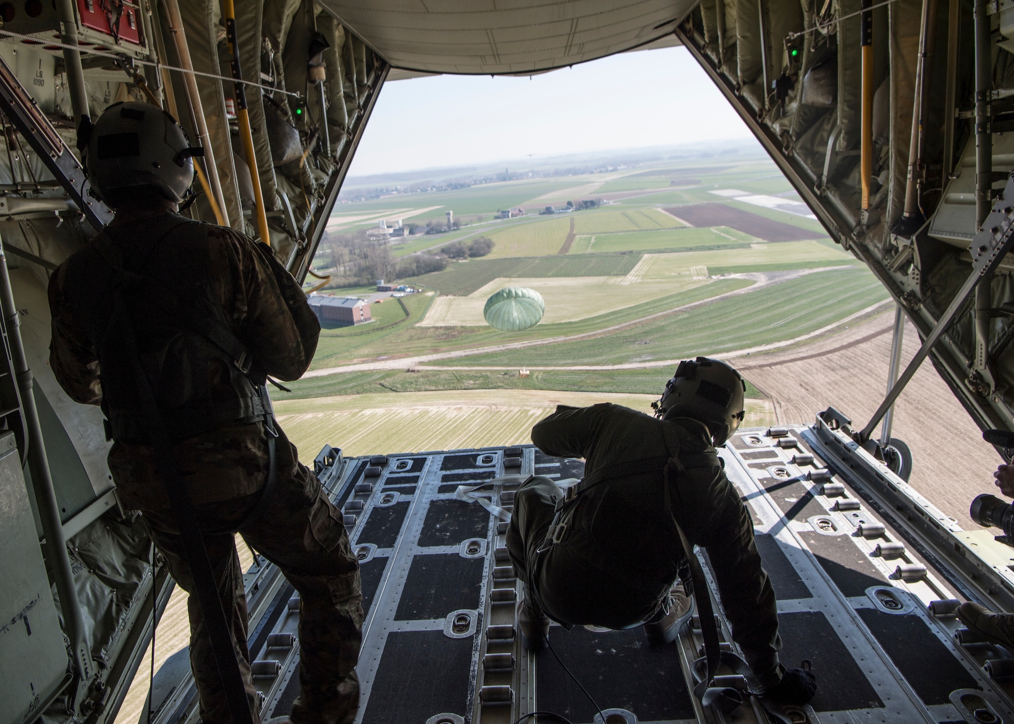 U.S. Air Force Staff Sgt. Brian Clark and Tech. Sgt. Alex Carlson, 37th Airlift Squadron loadmasters, push an airdrop package out over Chievres Air Base, Belgium, March 26, 2020.