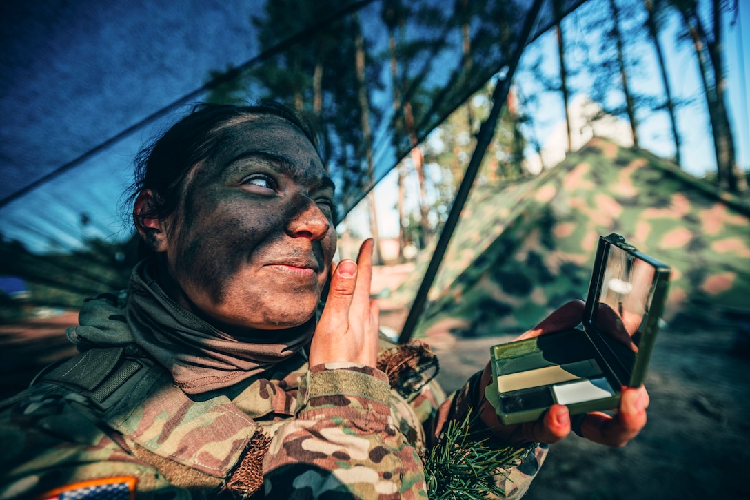 A soldier applies face paint.