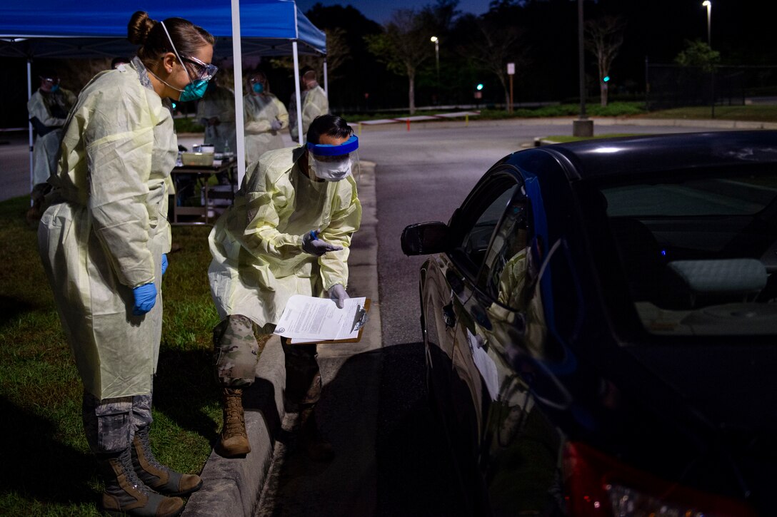 Photo of Airmen asking an active duty Airman questions during a COVID-19 Tier 2 screening.