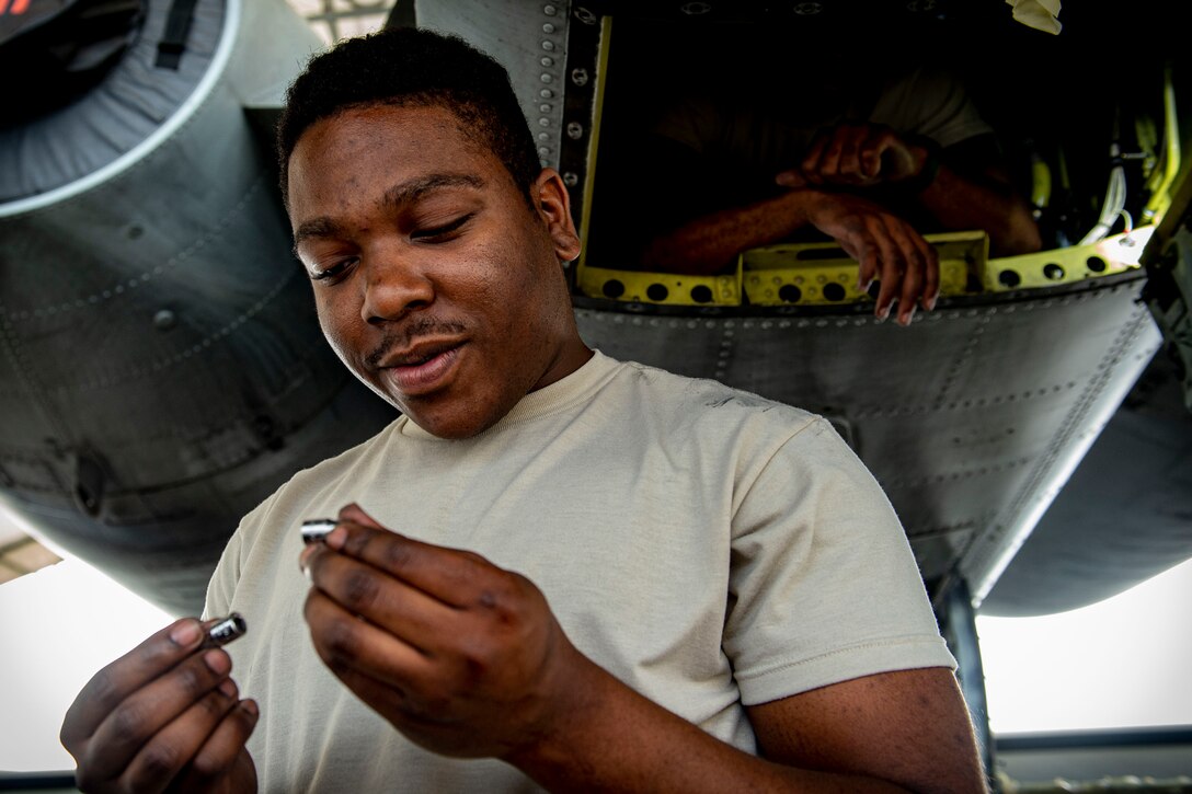 Photo of an Airman picking up bolts.