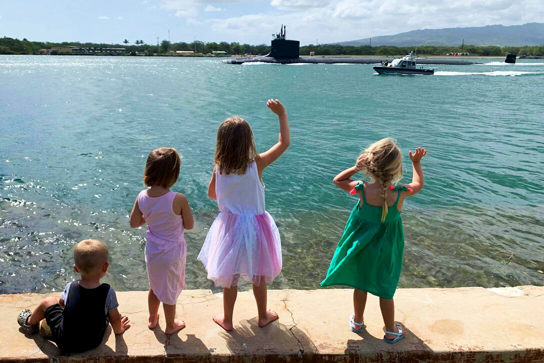 Four children look toward a submarine; two wave.