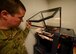 An Airman opens the cover to a 3D printer.