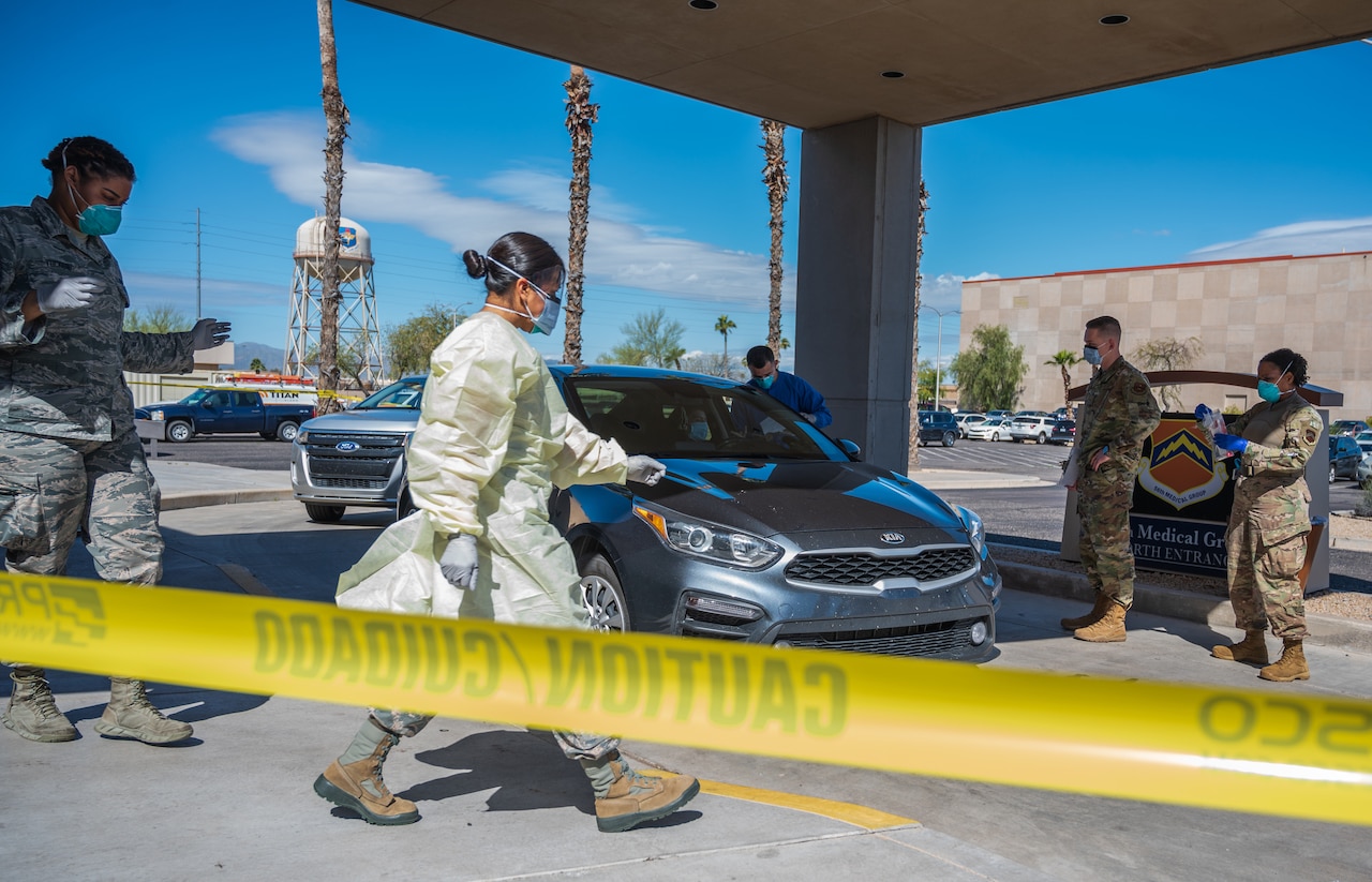 People with face masks walk around a car.