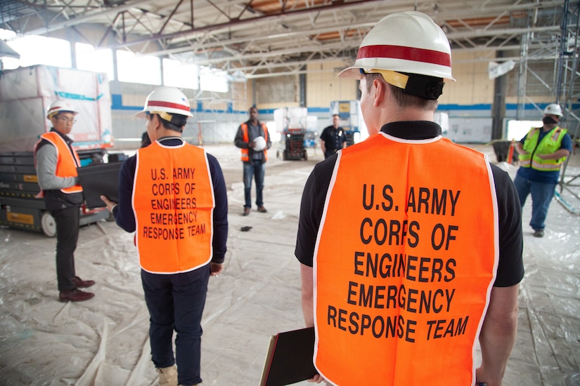Men in safety gear in a large, empty building.