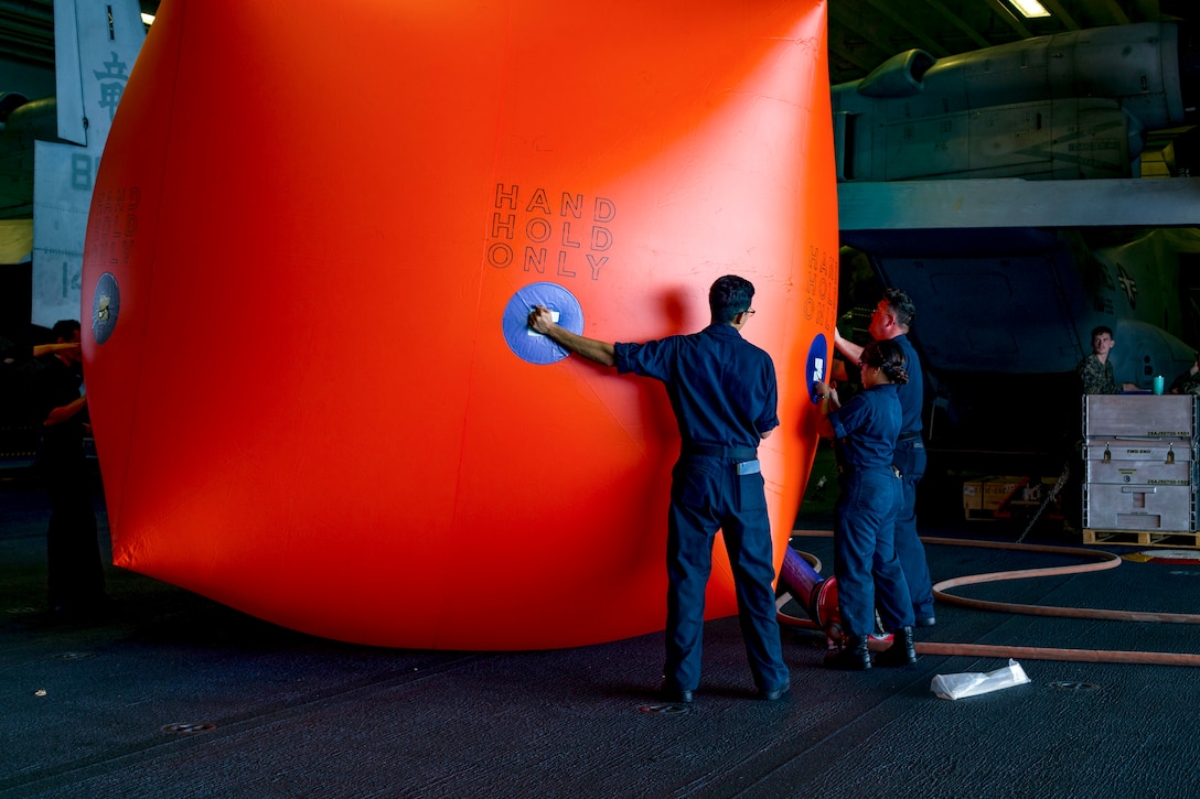 Sailors inflate a large orange-ish red target.