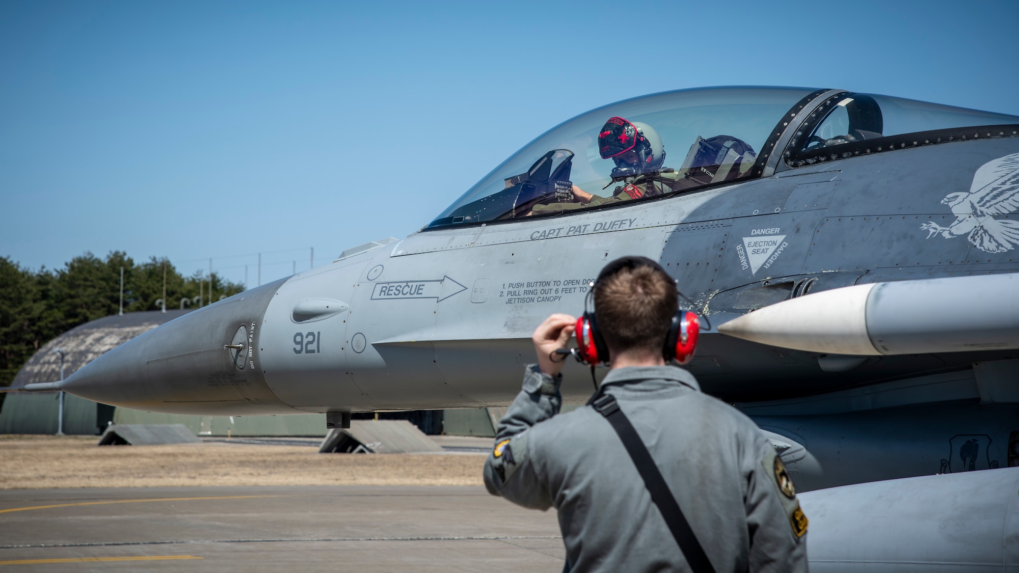 U.S. Air Force Senior Airman Kyle Greyshock, a 13th Fighter Squadron avionics systems journeyman, talks to Capt. Reese Black, the 13th FS chief of mobility, via radio headset at Misawa Air Base, Japan, March 30, 2020. The F-16 is a compact, multi-role fighter aircraft that has proven itself in air-to-air and air-to-surface attacks. Airmen are working around the clock ensuring aircraft are ready for flight training operations in order to promote a free and open Indo-Pacific. (U.S. Air Force photo by Airman 1st Class China M. Shock)