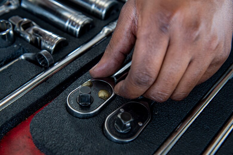 Photo of an Airman picking up a wrench.