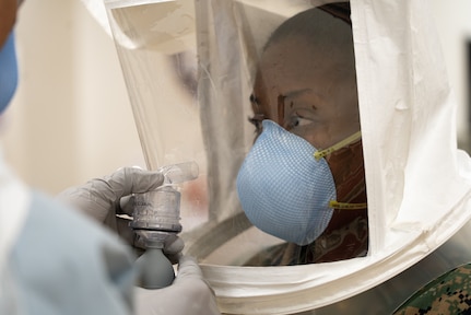 A soldier sprays an irritant into a mask.