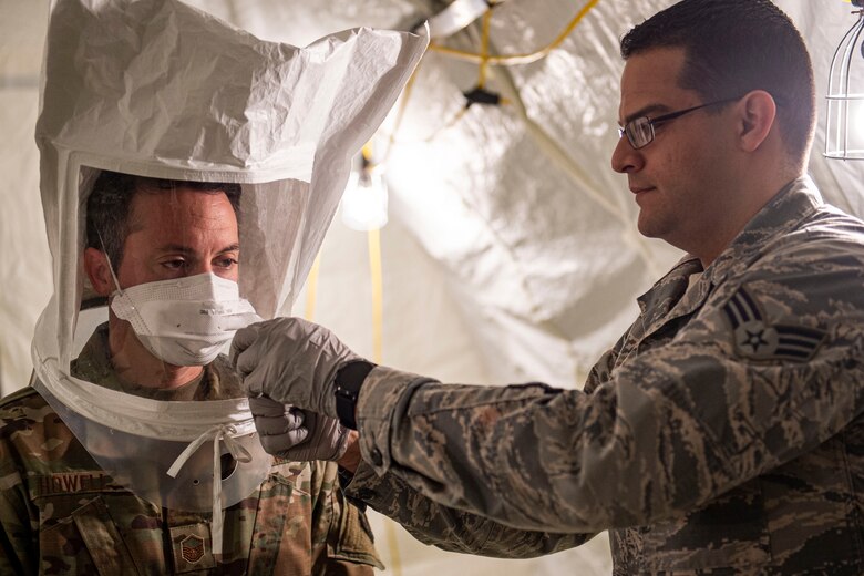 Photo of an Airman performing a protective-mask fit test on another Airman.