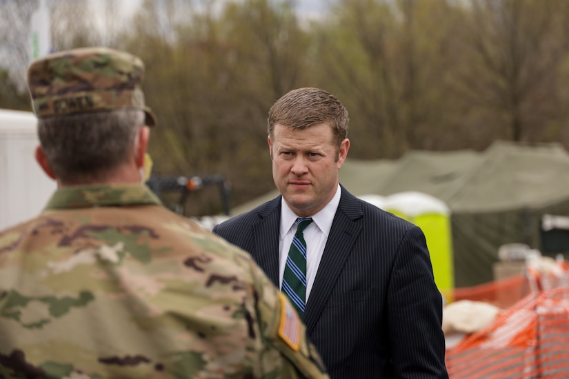 A civilian speaks to a National Guardsman at an outdoor site.