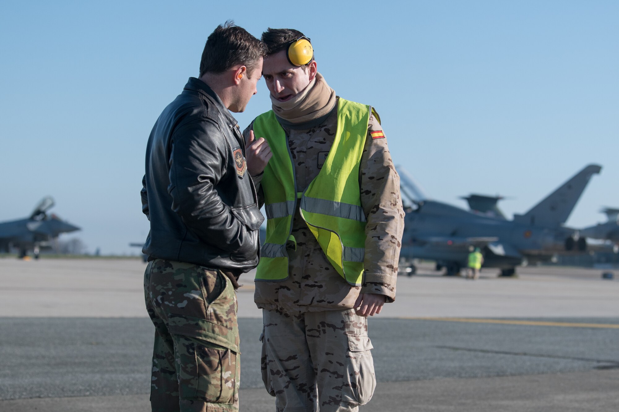 Capt. Travis Parrott, 3rd Airlift Squadron C17 Globemaster pilot, speaks with a member of a Spanish air crew during final pre-flight preparations for eight Eurofighter Typhoons, March 26, 2020, at Dover Air Force Base, Delaware. The U.S Air Force and it’s Air Mobility Command welcome the opportunity to support our international partners and Allies as they respond to impacts of the COVID-19 pandemic. Dover Air Force Base hosted more than a dozen aircraft as they return to their home countries following the cancellation of Exercise Red Flag at Nellis AFB, Nevada. Through intense internal coordination and in collaboration with interagency partners, all of the affected aircraft have been approved to redeploy to their host nations. Dover continues to prioritize the safety of our service members and community as we support the safe return of our NATO partners. (U.S. Air Force photo by Mauricio Campino)