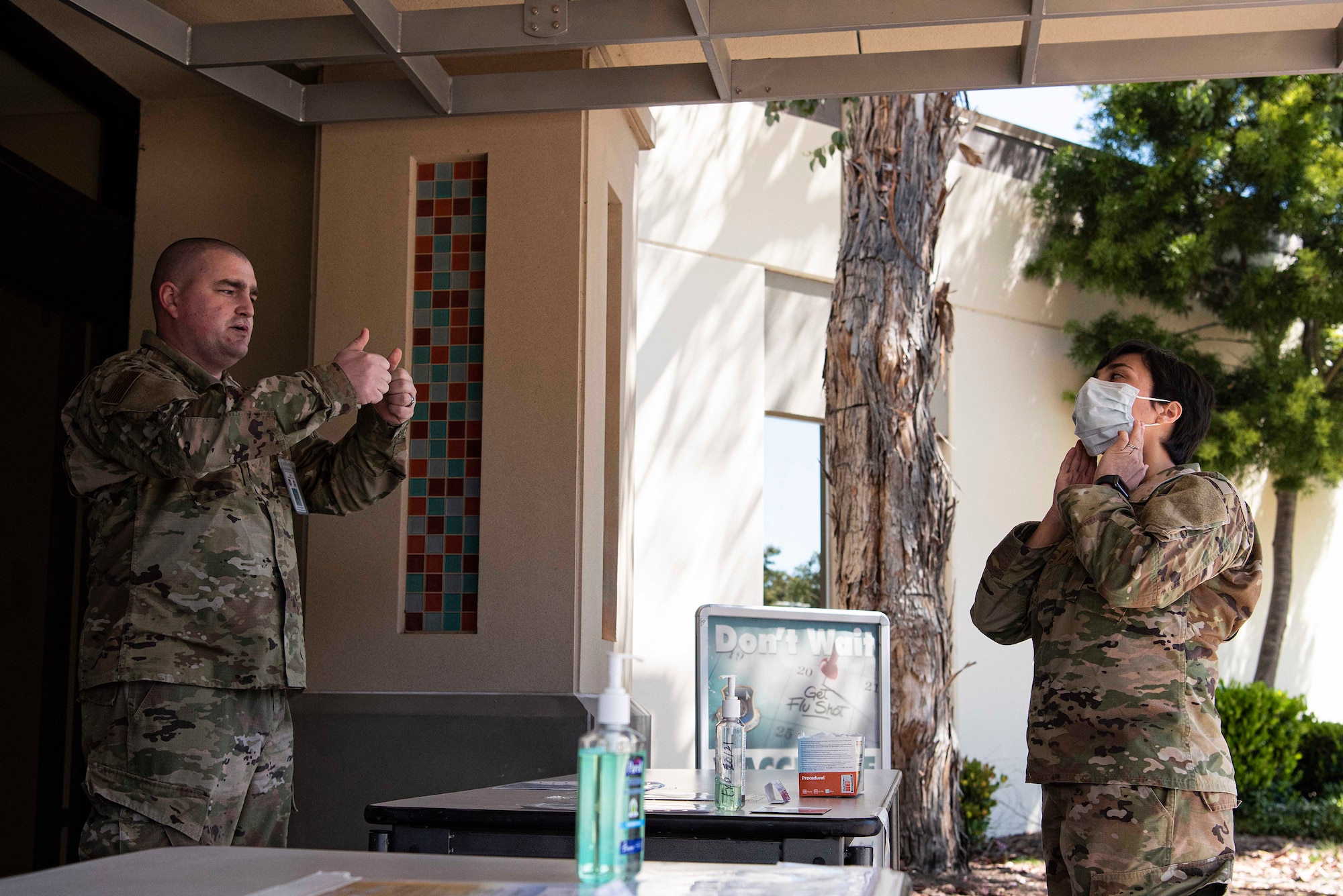 Staff Sgt. Joshua Gowan, 30th Medical Group NCO in charge of Biomedical Equipment Repair, instructs Maj. Aubrey Reid, 30th MDG nurse, on how to properly wear a procedural mask at the 30th MDG COVID-19 screening point March 30, 2020, at Vandenberg Air Force Base, Calif. While the 30th MDG is providing COVID-19 screenings primarily over the phone, they have set-up a physical screening point, at the front entrance, for individuals entering and exiting the medical building as a second barrier to prevent the spread of the virus. At the screening point, members are asked a series of questions to ensure they do not have any symptoms of COVID-19. (U.S. Air Force photo by Airman 1st Class Hanah Abercrombie)