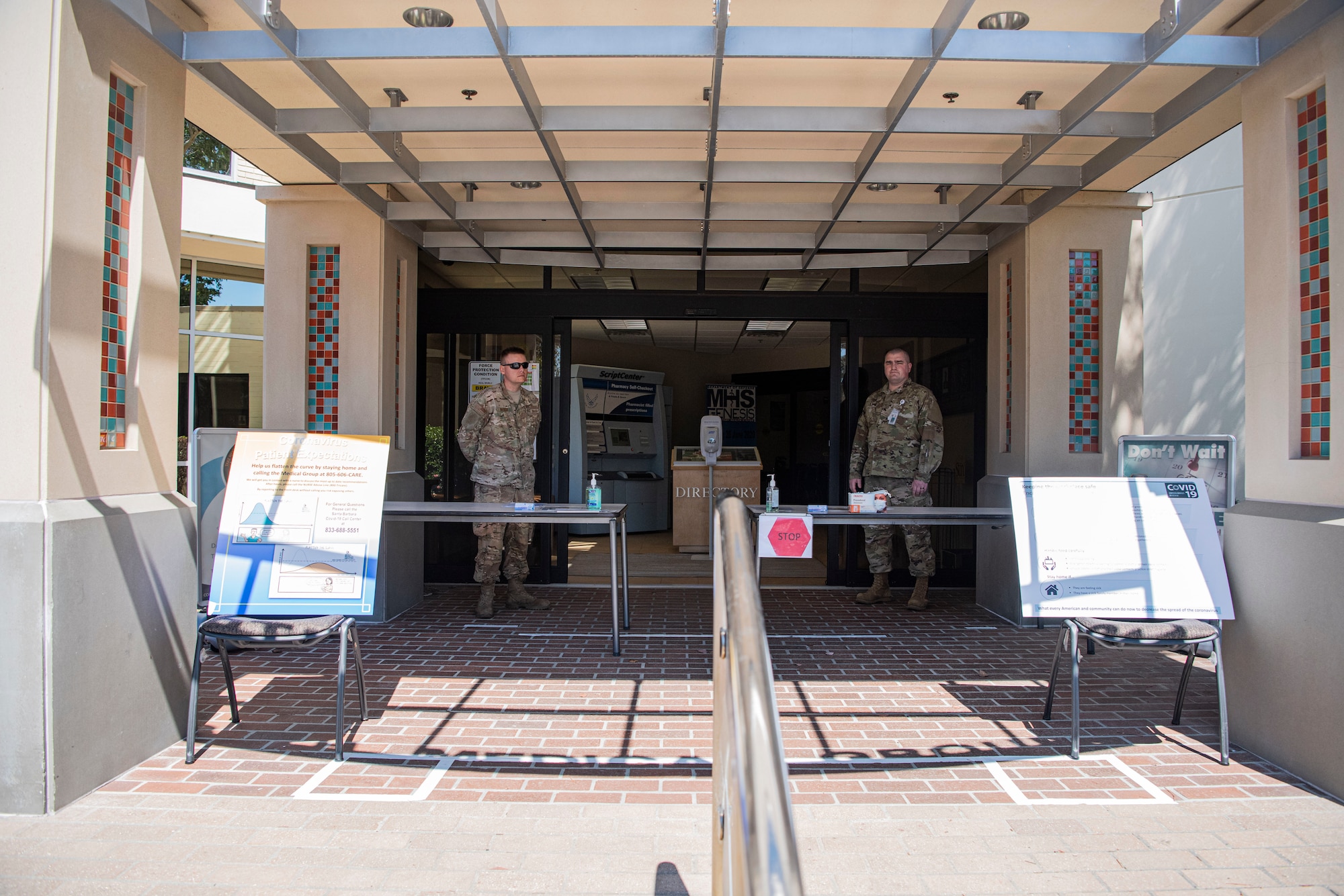 Members of the 30th Medical Group prepare for customers to enter through the COVID-19 screening point March 30, 2020, at Vandenberg Air Force Base, Calif. The screening point, located at the main entrance of the 30th MDG, serves as a health checkpoint for those entering and exiting the facility. During the screening, members are checked for symptoms of COVID-19, such as a cough and fever, and are provided masks if any symptoms are present to help prevent the spread the virus. (U.S. Air Force photo by Airman 1st Class Hanah Abercrombie)