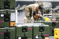 A soldier unloads equipment.