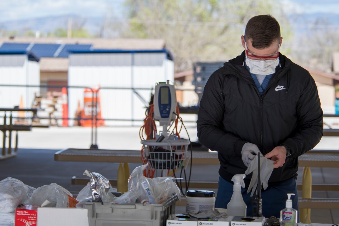 Airman 1st Class Josh Brinegar, 49th Medical Operations Squadron aerospace medical technician, puts on gloves at the 49th Medical Group’s medical screening area on Holloman Air Force Base, N.M., March 20, 2020. Holloman medical professionals set up the designated medical care station outside of the medical group building in order to screen patients and limit foot traffic inside the clinic. (U.S. Air Force photo by Senior Airman Collette Brooks)