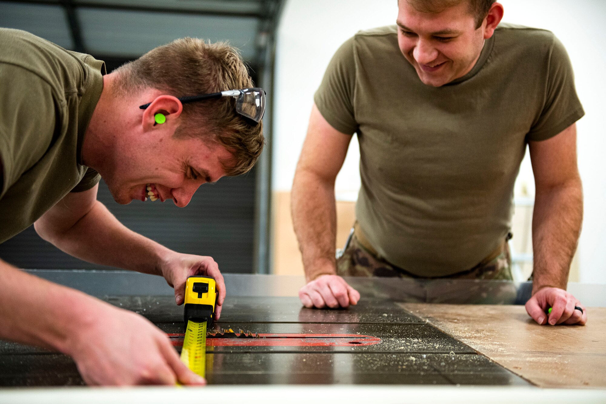 Photo of Airmen measuring cutting length for plexiglass.