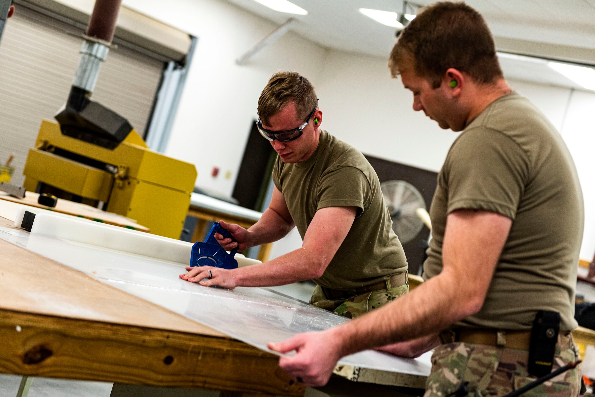 Photo of Airmen cutting plexiglass.