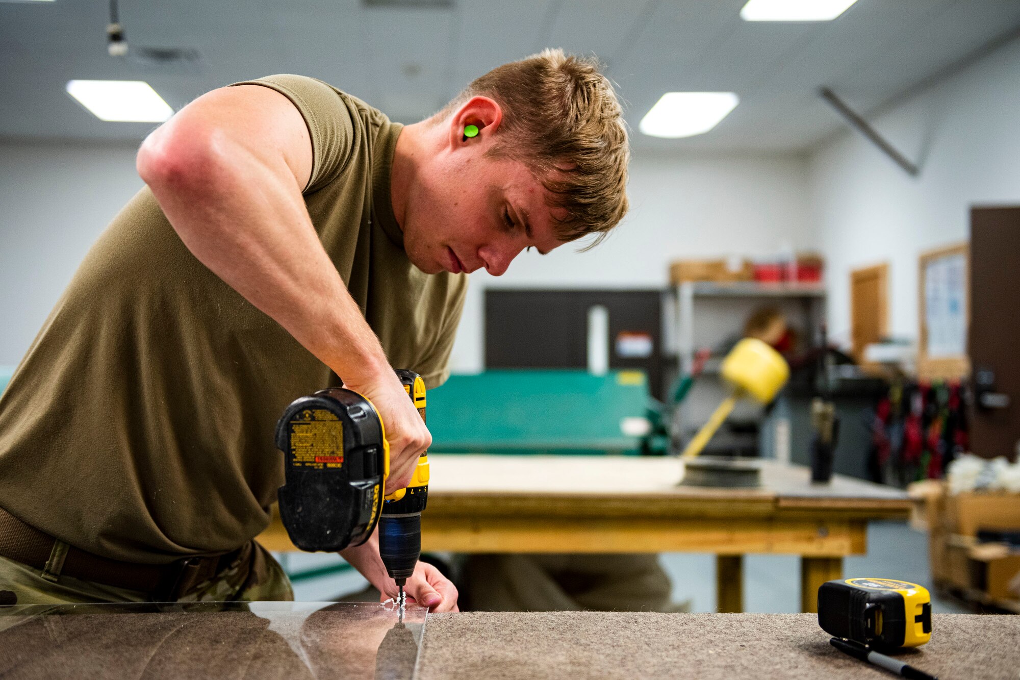 Photo of Airman drilling holes into plexiglass.