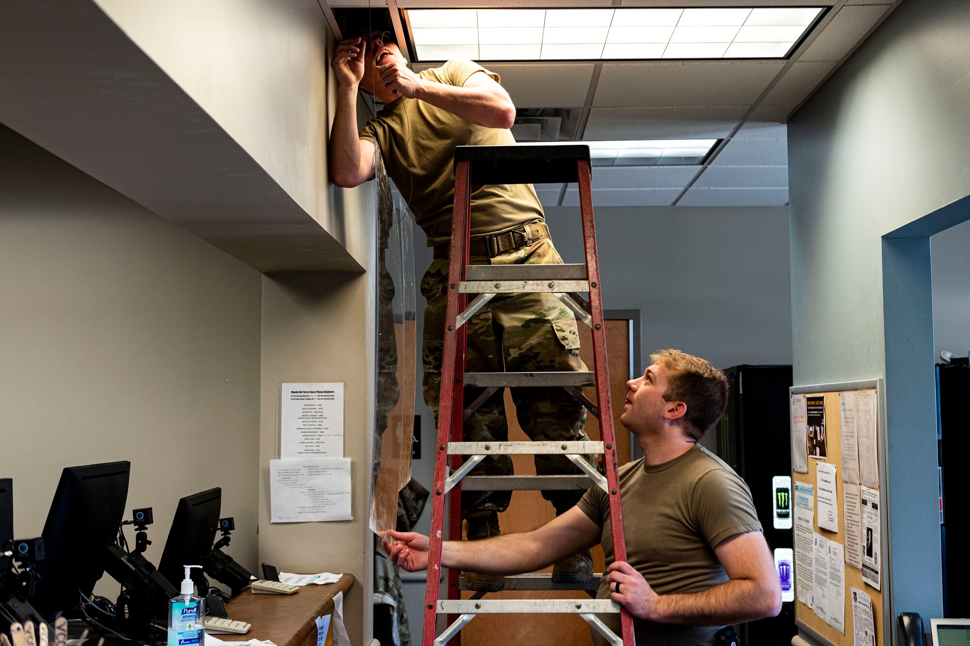 Photo of Airmen installing plexiglass barriers.