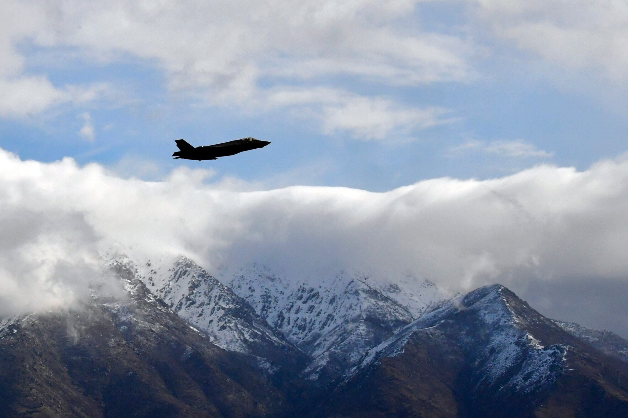 An F-35 takes off near the Wasatch Mountains on a cloudy day