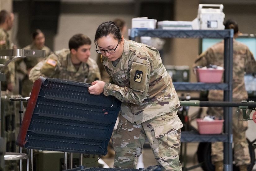 Soldiers build shelving and unload medical equipment.