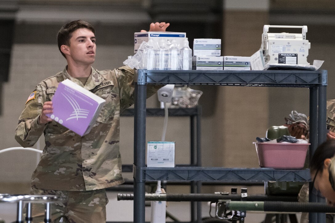 A soldier puts medical equipment on a shelf.