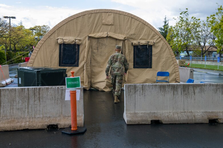 A U.S. Air Force Airman walks toward a COVID-19 testing site March 25, 2020, at Travis Air Force Base, California. The testing location, which is located outside the emergency room of David Grant USAF Medical Center, is one of two sites the base is providing to support COVID-19 testing. (U.S. Air Force photo by Tech. Sgt. James Hodgman)