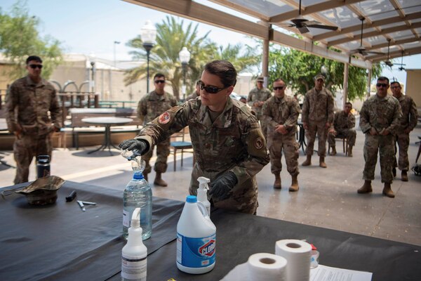 An airman makes a cleaning solution while other service members watch.