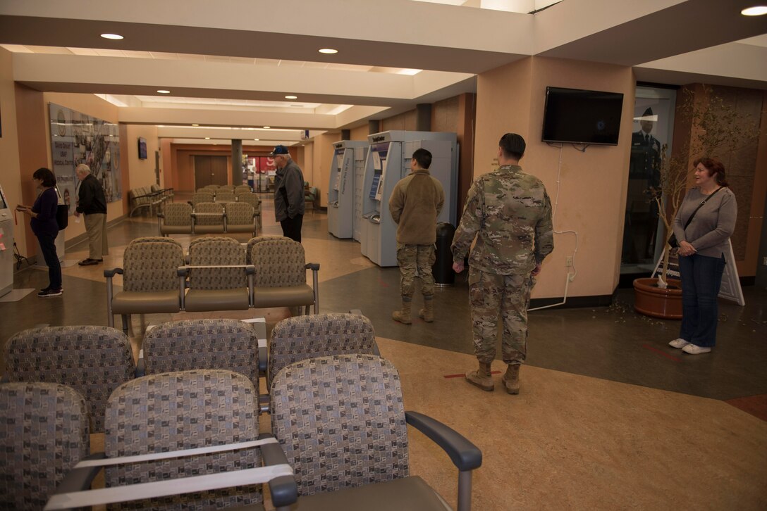Base Exchange Satellite Pharmacy customers wait in line to use a pharmacy kiosk while practicing physical distancing measures March 30, 2020, at Travis Air Force Base, California. Travis AFB pharmacies implemented multiple procedures to combat COVID-19, including placing red tape on the floor that encourages a safe distance between each person in line. (U.S. Air Force photo by Airman 1st Class Cameron Otte)