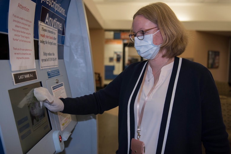 Jacqueline Bradford, 60th Medical Group office assistant, disinfects the prescription refill kiosk March 30, 2020, at Travis Air Force Base, California. Travis AFB pharmacies implemented multiple procedures to combat COVID-19, including wiping down surfaces that are commonly touched by people. (U.S. Air Force photo by Airman 1st Class Cameron Otte)